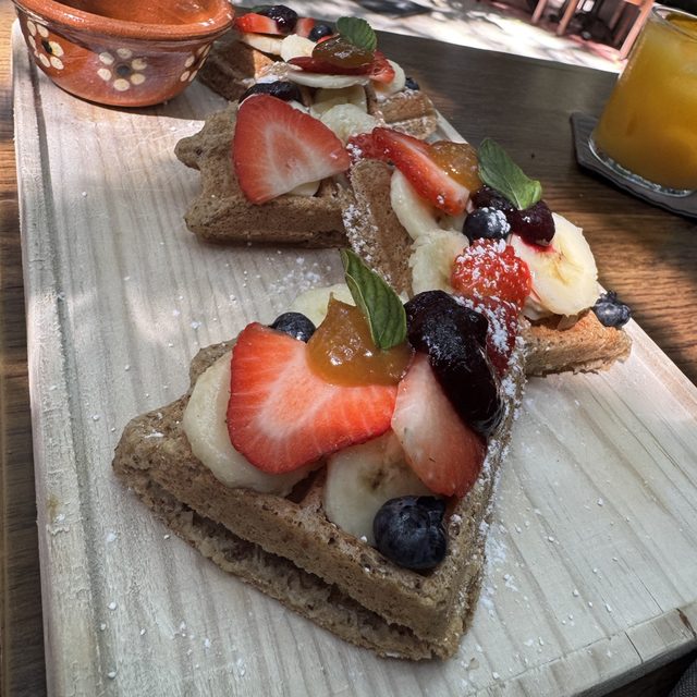 Waffles con las mesas del jardín selvático de ARCANA al fondo
