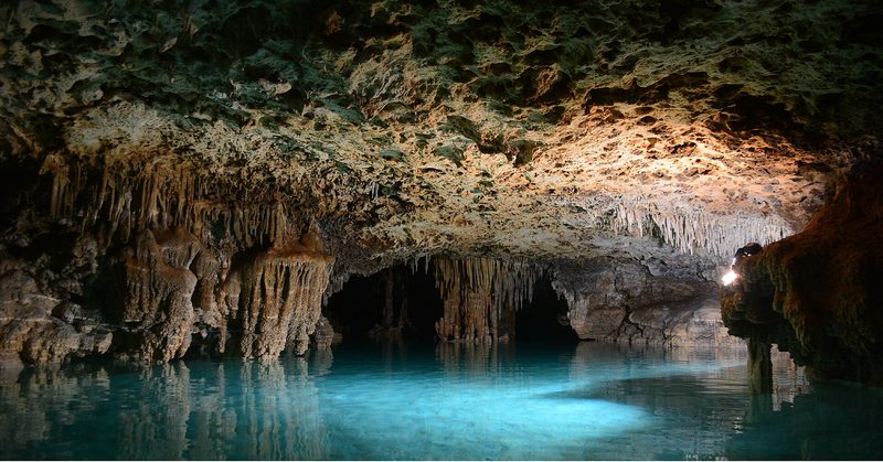 Inside the Río Secreto cave, Quintana Roo: stalactites above clear turquoise water.