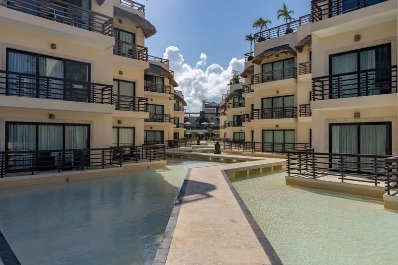 Shallow water garden with a stone walkway between the balconies of the Aldea Thai building